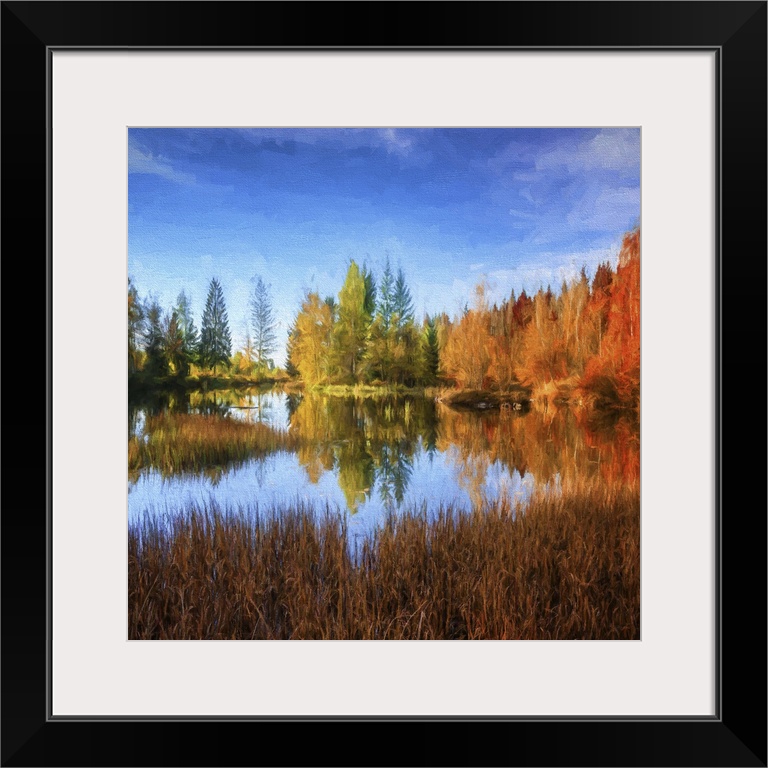 A peaceful pond in the middle of a forest in fall colors under a deep blue sky.