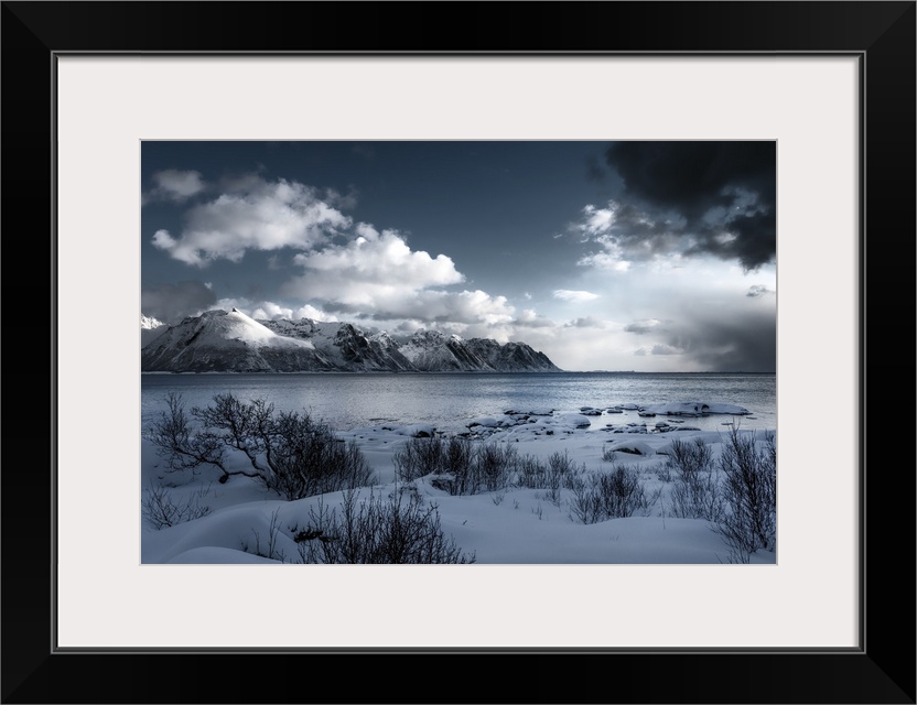 A photograph of a mountain range seen from across a lake in winter.