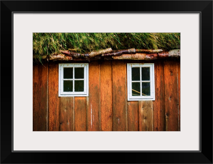 Two little windows in a wooden wall with a grassy roof.