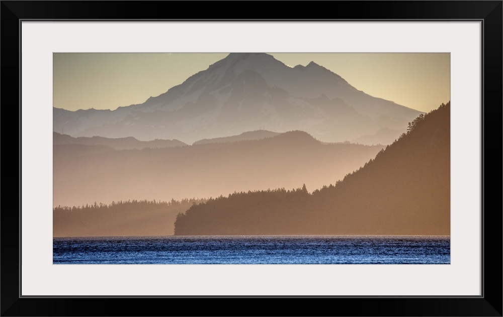 Mist surrounding the mountains on the Washington coast in dim sunlight with the bright blue ocean in the foreground.