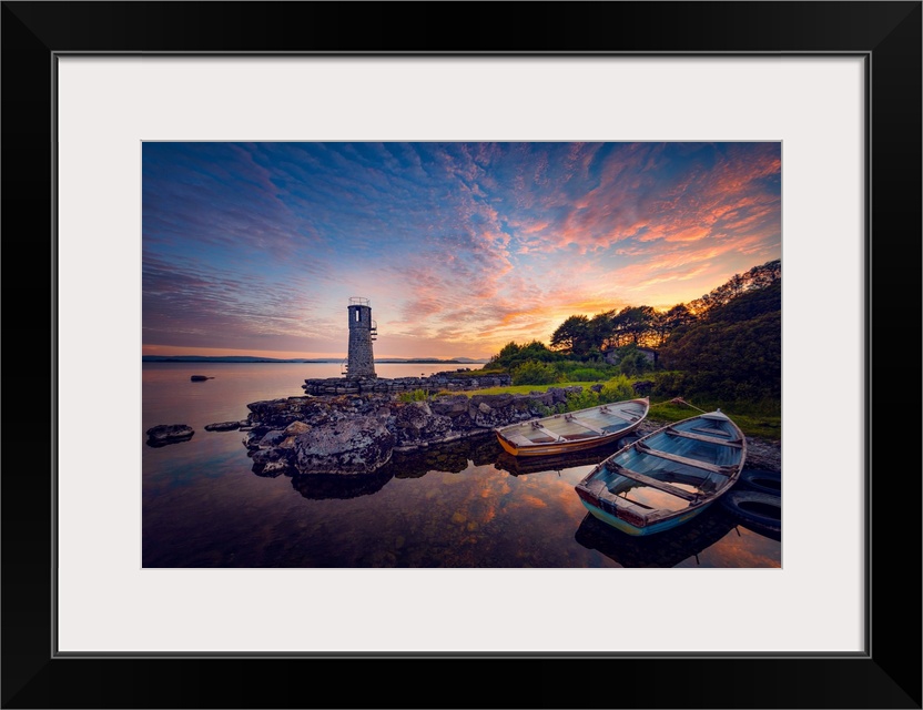 Sunset in Ireland with rowing boats in the foreground around a lighthouse