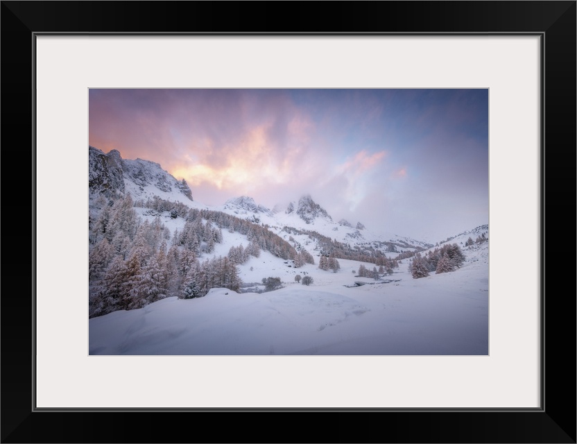 Colored sunset landscape scene on a snowy mountain in the Alpes in France. A pine valley in winter during a quiet moment.