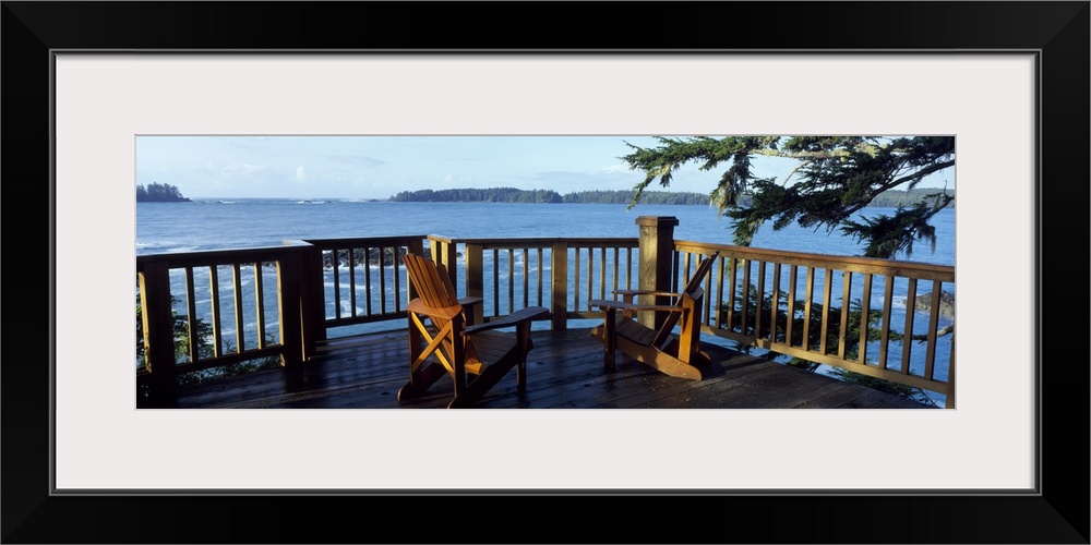 Two chairs sit on a raised deck overlooking a large body of water.