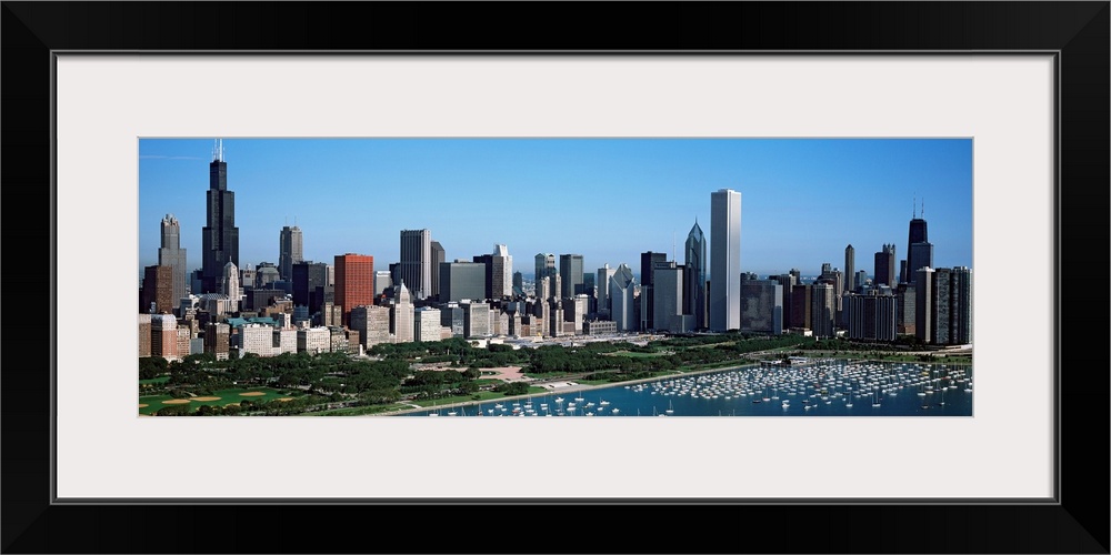 This panoramic photograph shows the city skyline and a crowded harbor on the lake on a sunny cloudless day.