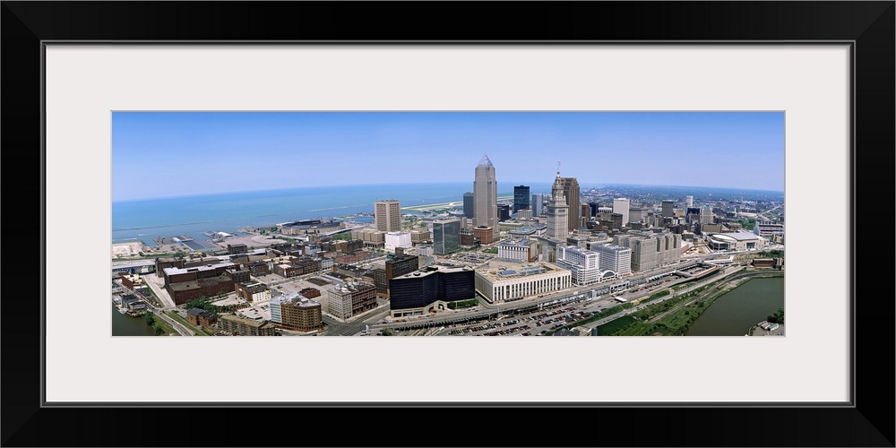 Horizontal, aerial photograph of the Cleveland Ohio skyline beneath a blue sky.