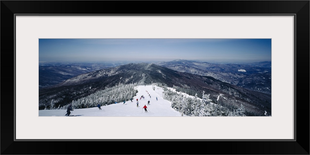 This is a panoramic photograph of skiers heading down a mountain covered with powdery snow in the Appalachian Mountains.