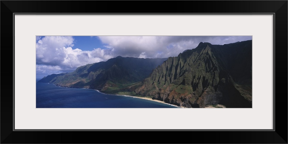 Panoramic photograph of mountainous shoreline under a cloudy sky.