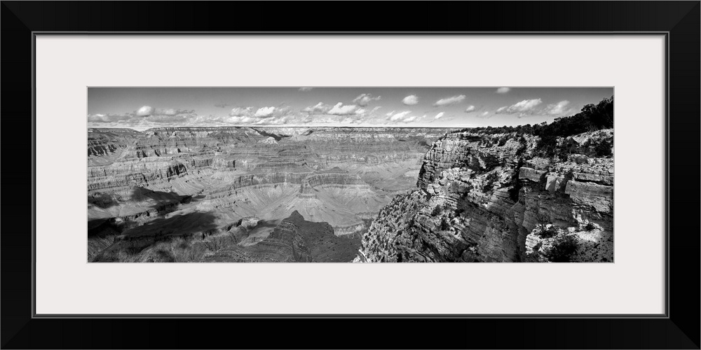 Panoramic photo on canvas of a view of the Grand Canyon seen from the top of a cliff with puffy clouds in the distance.