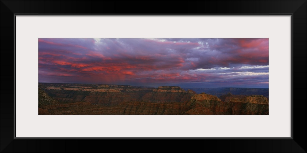 Panoramic photo taken on the rim of the Grand Canyon looking out towards the other side as clouds roll in at sunset creati...