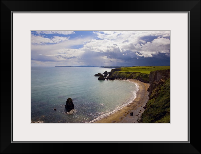 An oversized piece taken from atop a hill looking out over the coast and ocean in Ireland with rock formations sitting in ...