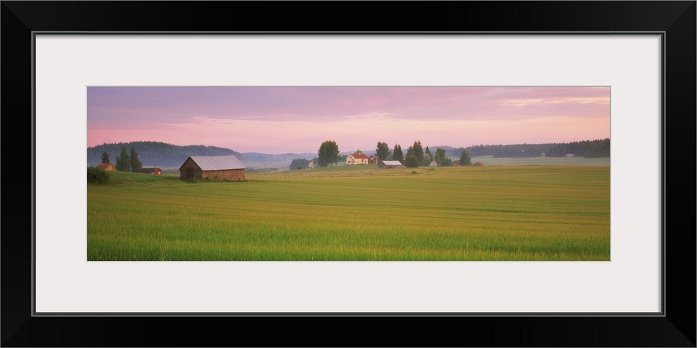 Barn and wheat field across farmlands at dawn, Finland