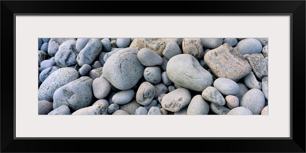 Up-close panoramic photograph of seaside pebbles and rocks.