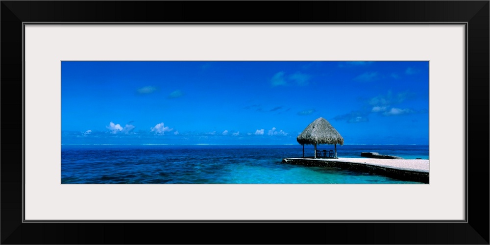 This large wall art is a sweeping panoramic photograph of the ocean horizon and a single shady shelter on the edge of the ...