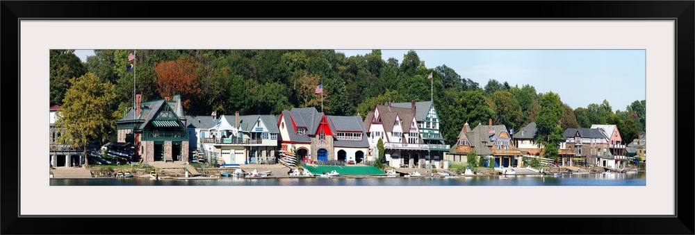 A panoramic photograph taken at midday in late summer of the boat houses that line the river.