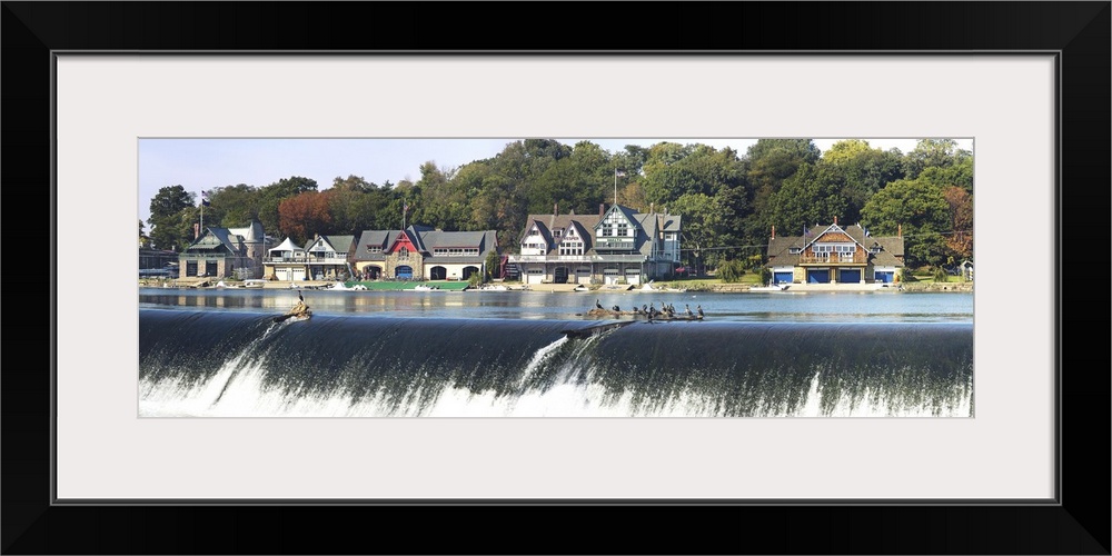 Row of five houses in an upper class neighborhood on the edge of a river, with several people in canoes at the top of the ...