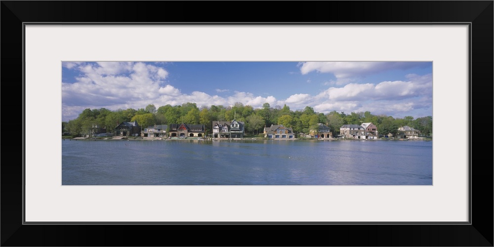 Panoramic photo of boathouses lining a waterfront.