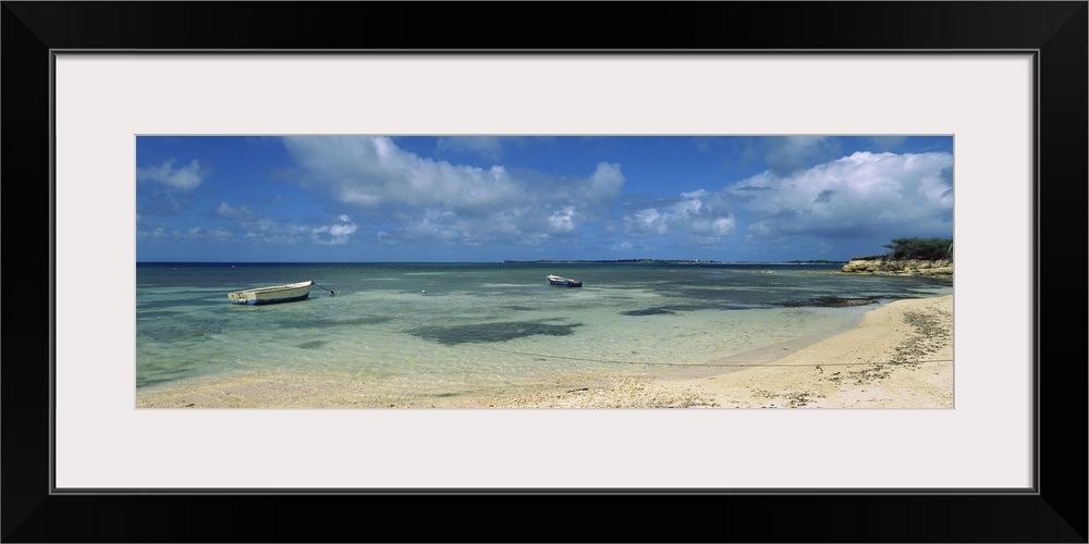 Long horizontal image on canvas of boats floating in the ocean near a shore.