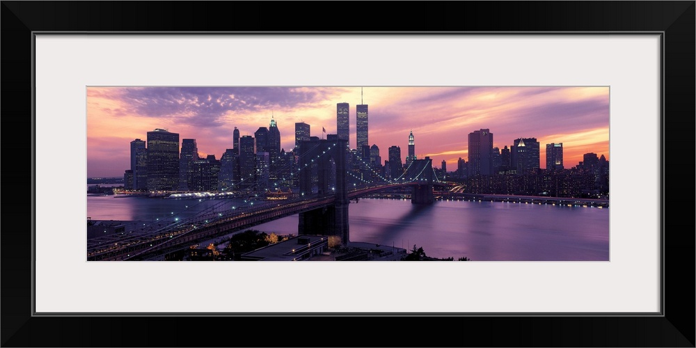 This wall hanging is a panoramic photograph captures the fading sun as skyscrapers begin to turn on their lights for the n...