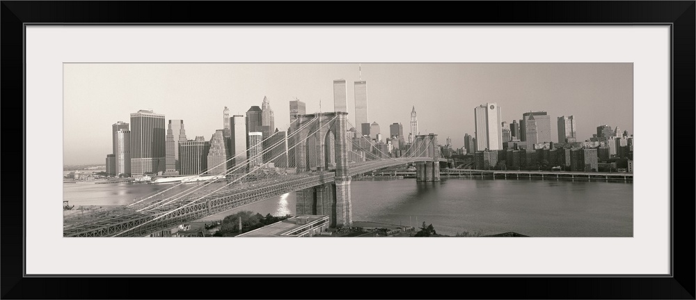 Panorama of Manhattan skyline and the Brooklyn Bridge in black and white and grayscale tones.