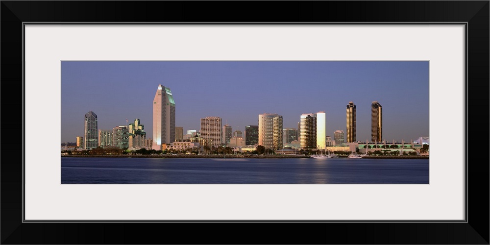 Wide angle photograph of the San Diego skyline over the water, beneath a blue sky during the day.