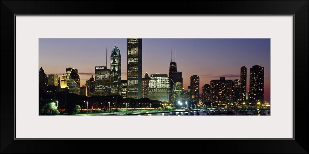 A wide angle picture taken of the Chicago skyline during sun down with the buildings illuminated.