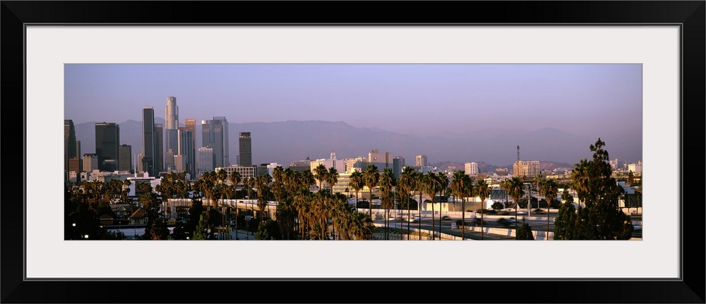 Panoramic photograph of cityscape under fog with mountain silhouette in the distance.