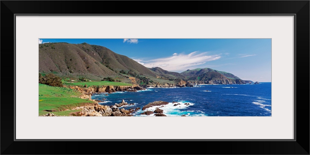 Wide angle photograph of the coastline in Big Sure, California.  Hills jutting into the blue waters of the Pacific Ocean.