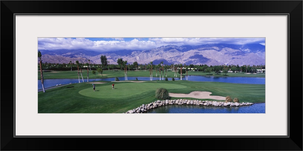 This panoramic photograph shows the immaculate oasis with mountains and clouds in the distance.