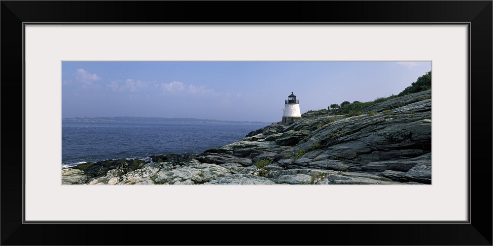 A small lighthouse sits on the edge of rocky terrain and overlooks the Atlantic ocean.