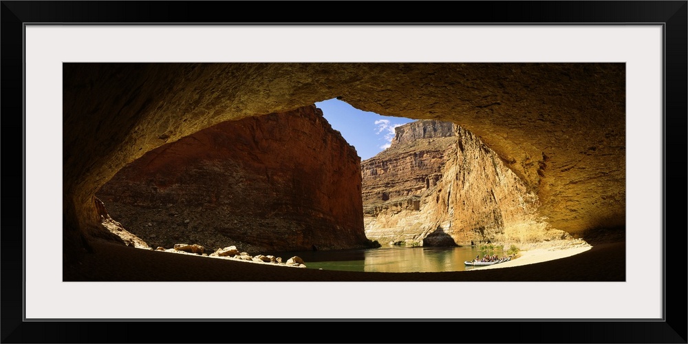Wide angle photograph, looking out of a large cave opening near the Colorado River in Arizona.  Large sandstone formations...