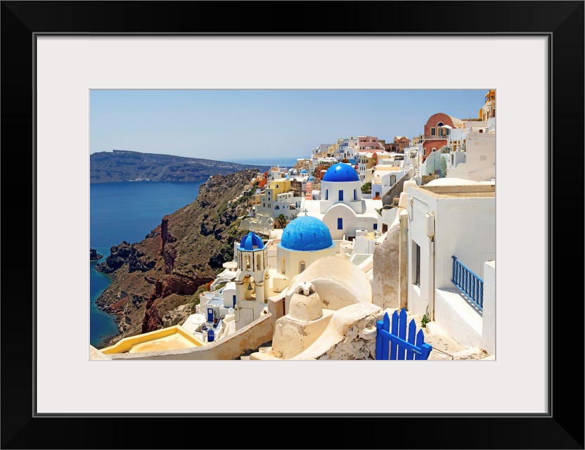 This hillside city with its famous colored roof tops overlooks a rocky Grecian sea in this panoramic photograph.