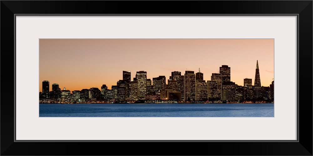 Horizontal image on canvas of the San Francisco skyline lit up at sunset by the water.