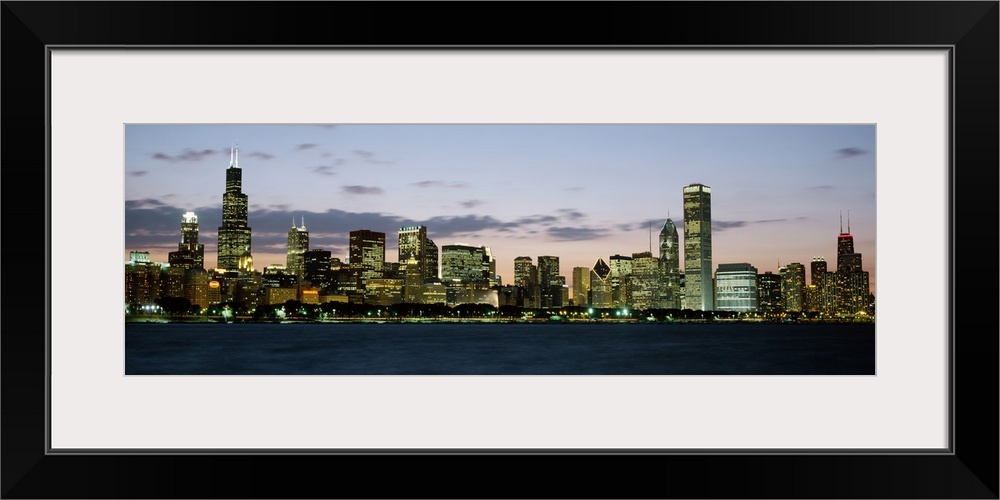 Panoramic photograph displays a horizon filled with tall skyscrapers and buildings as the sun begins to set on the largest...