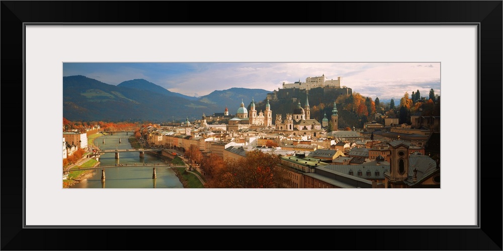 Buildings surrounded by a body of water and mountainous terrain in Austria are photographed in wide angle view.