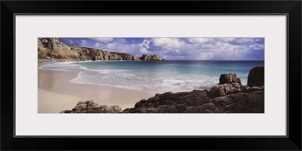 Wall docor of large rock formations meeting a beach with a crystal clear ocean.