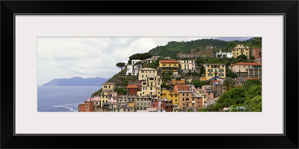 This panoramic landscape photograph of homes built into the hillside overlooking the sea.