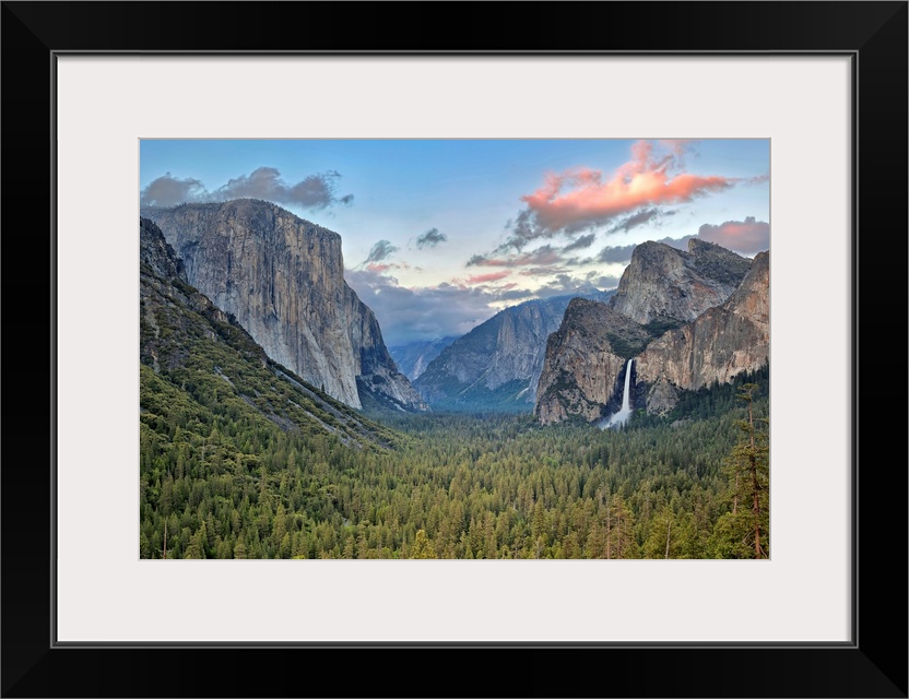 Landscape photograph on a big canvas of Yosemite Valley, green tree tops surrounded by mountains, a large waterfall can be...
