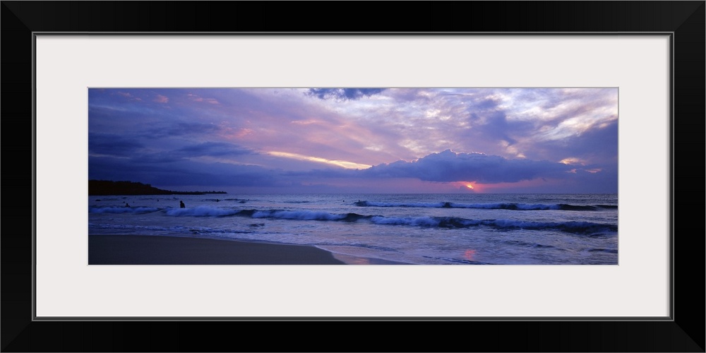 This big picture is a panoramic photograph of the ocean surf sweeping over the shore. The sun fills the sky with pastel co...