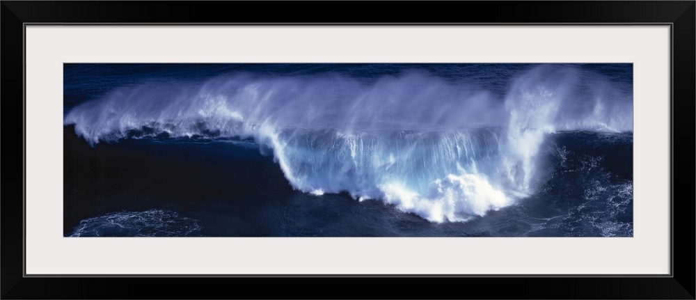 Wide angle shot of a huge wave that has begun to crash down.