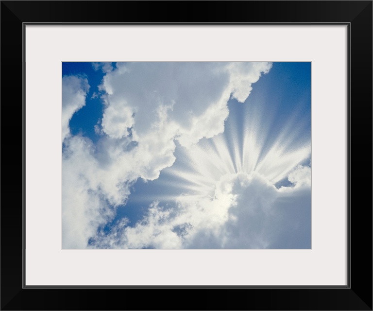 Large photograph of the sky on a cloudy day with the sun's rays about to break through.