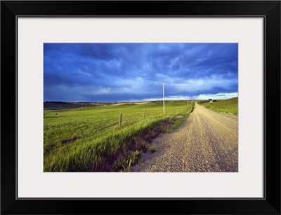 Dirt road through farmland, distant storm clouds, Missouri Breaks, Montana
