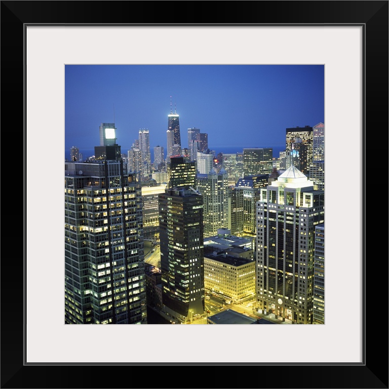 Square photo print of tall buildings in downtown Chicago lit up at night.