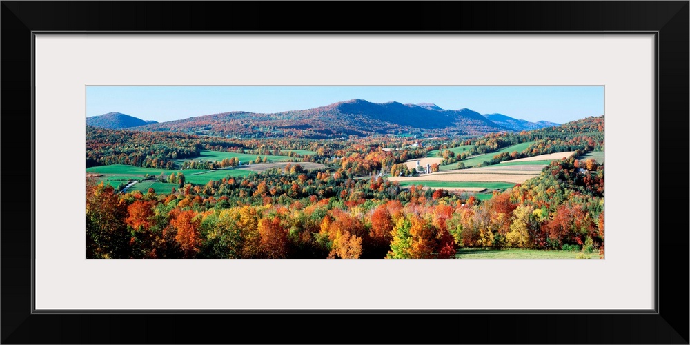 A valley in New England filled with open pastures and accented with trees covered with leaves turning in autumn.