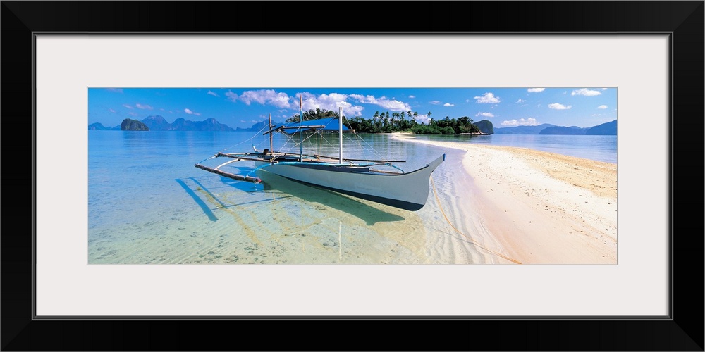 Panoramic photograph displays a fishing vessel as it sits docked on the sandy shores of a coastal region within the Sulu S...