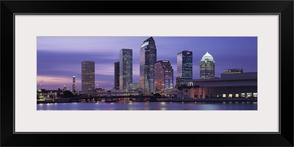 Panoramic photograph taken at nighttime of a group of skyscrapers within a busy city in the Southeastern United States.  T...