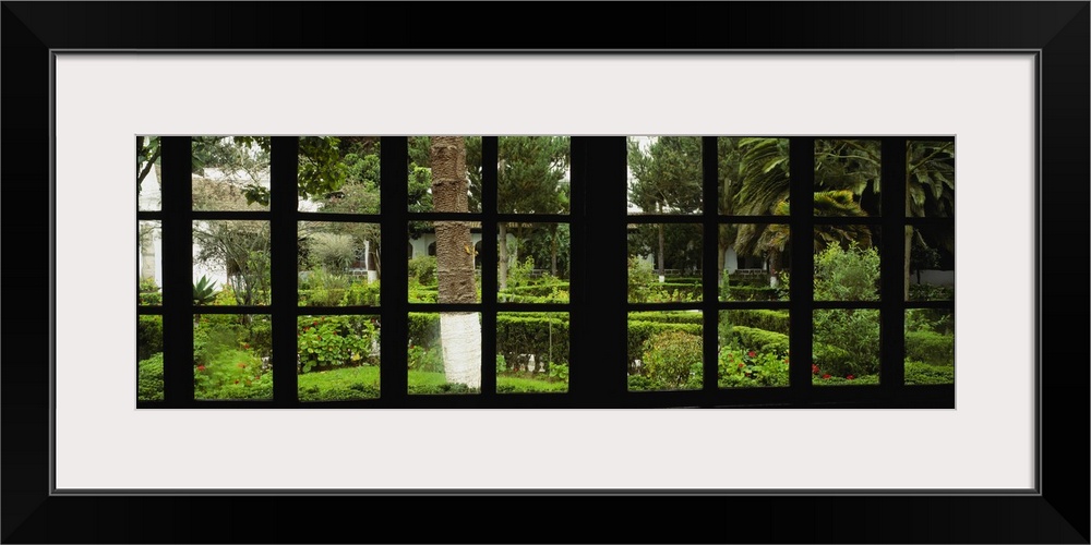 Panoramic image looking out of a silhouetted window into a garden.