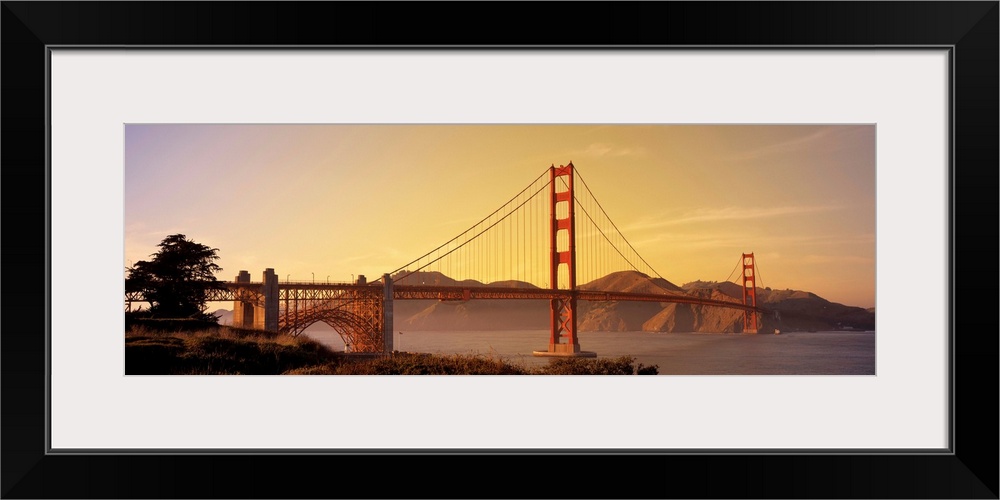 Giant horizontal photograph of San Francisco Bay's suspension bridge, the Golden Gate Bridge, at sunrise.