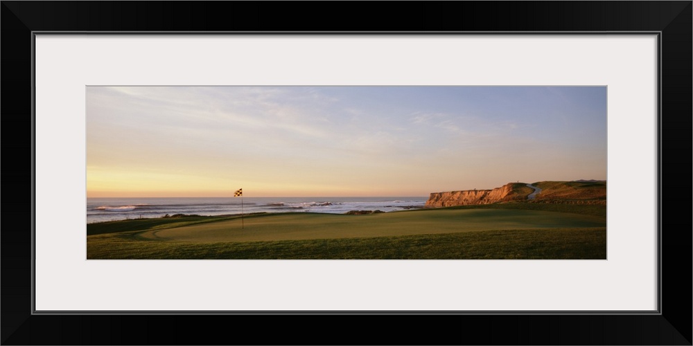 Panoramic photograph on a large canvas of the green on a golf course, along the coast of Half Moon Bay in California.