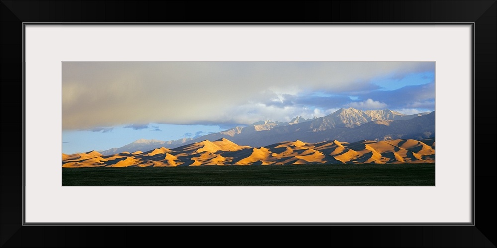 Sand dunes in a desert with a mountain range in the background, Great Sand Dunes National Park, Colorado, USA