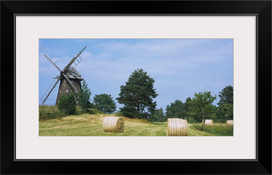 Hay bale in a field with a traditional windmill in the background, Riddarfjarden, Narke, Sweden